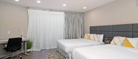 A hotel room with two beds, a desk, and a chair.