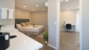 Un dormitorio moderno con cama, mesita de noche y zona de escritorio.