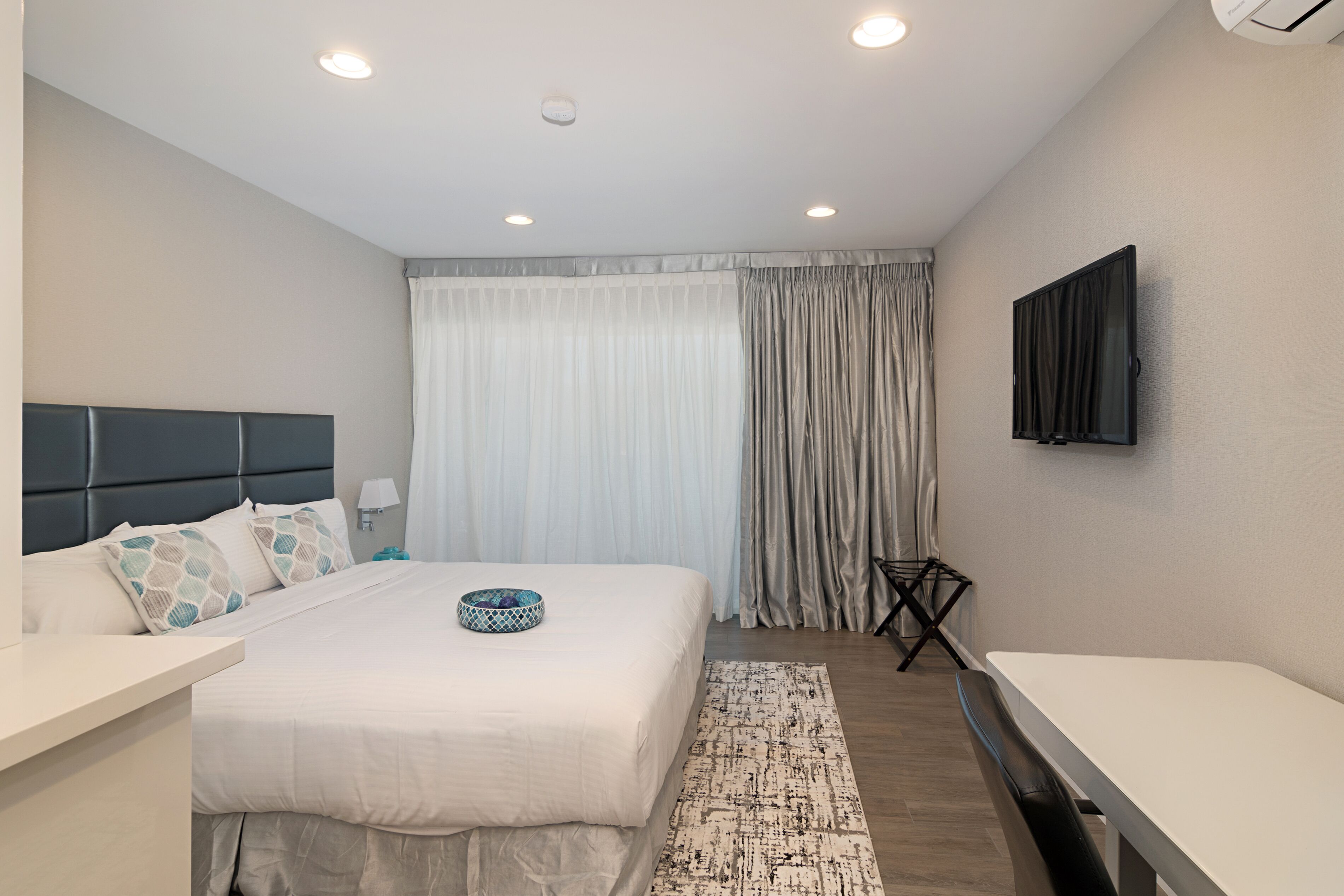 A modern hotel room with a large bed, a flat-screen TV, and a small table.