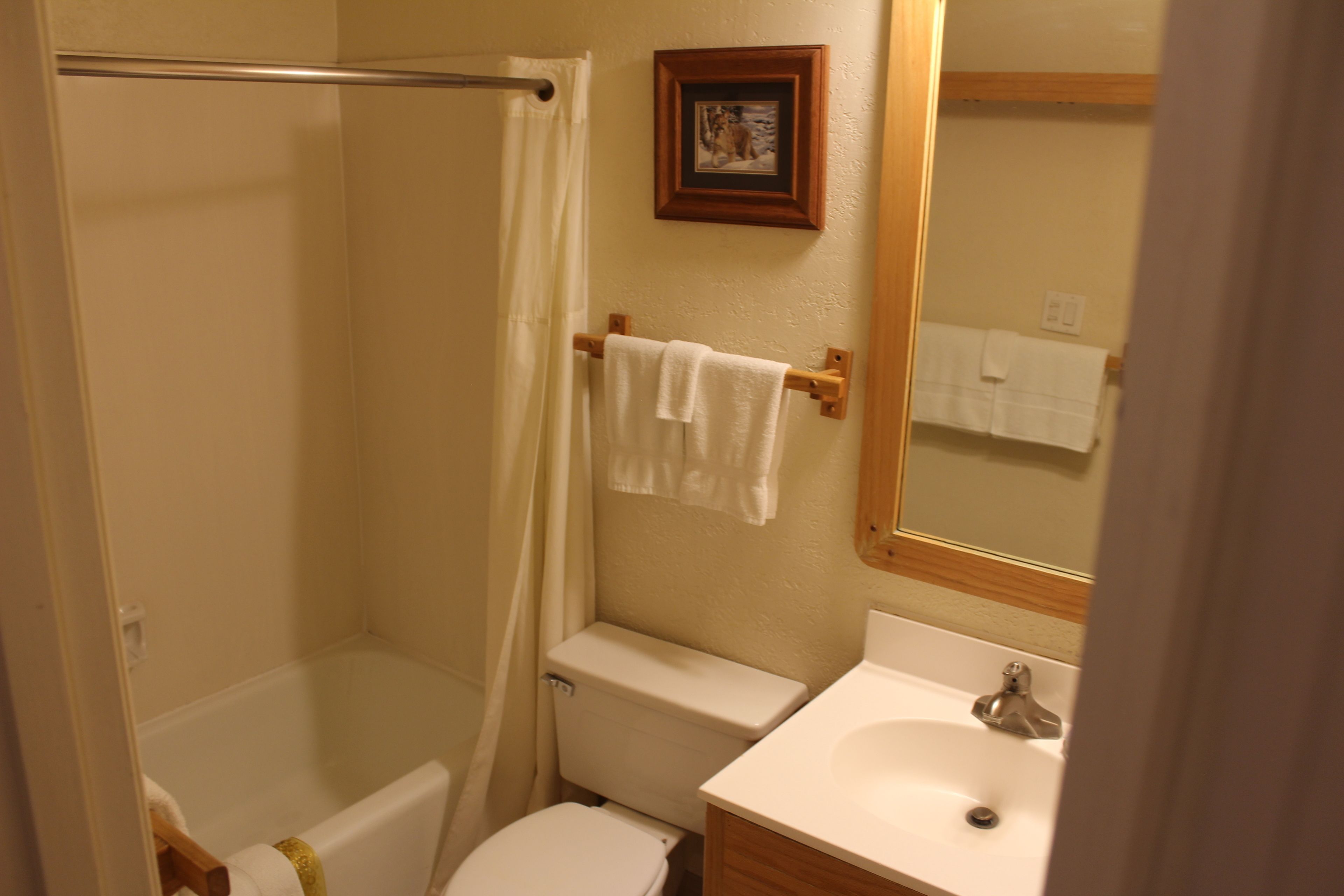 A bathroom with a bathtub, toilet, sink, and a framed picture on the wall.