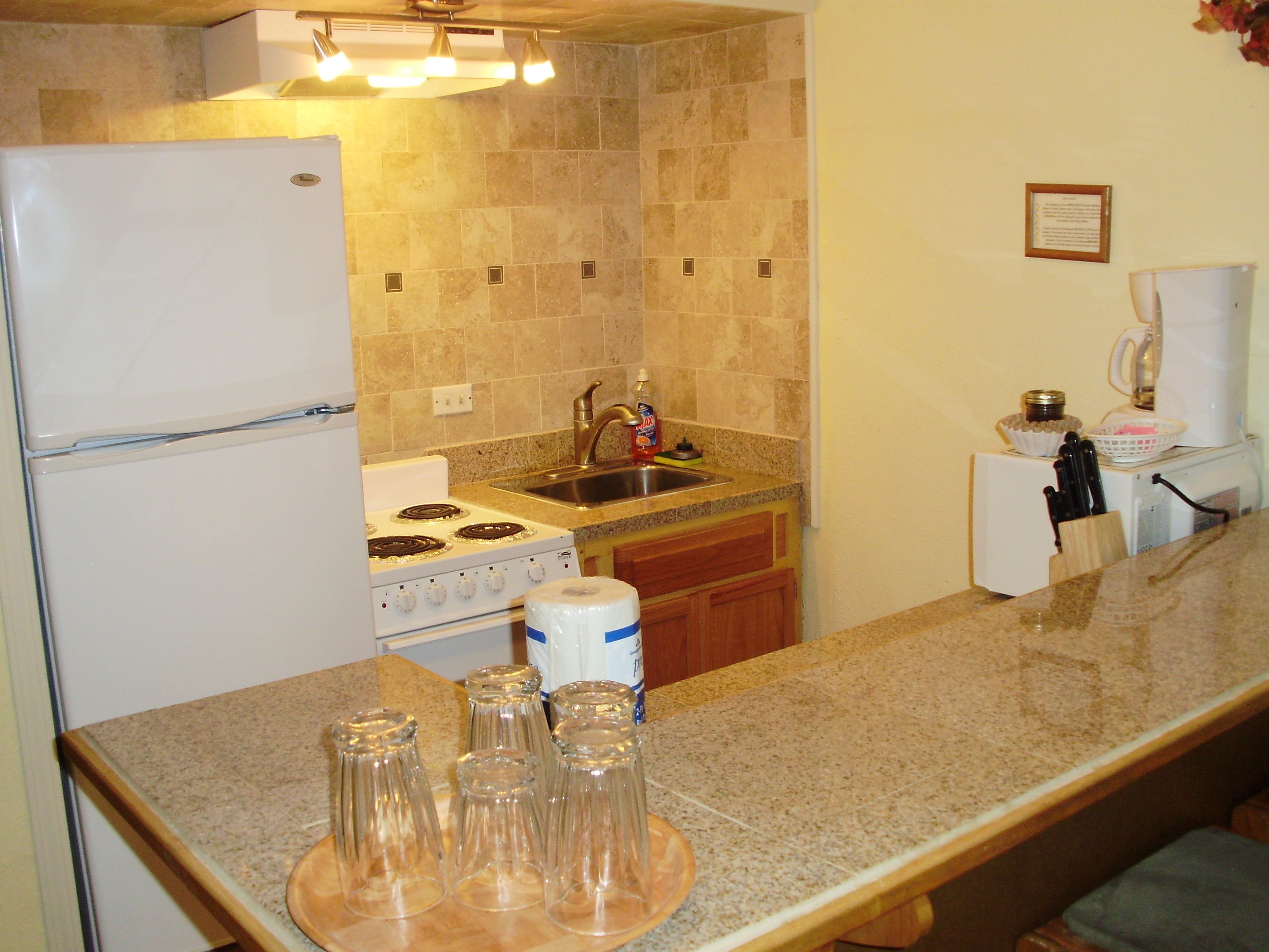 A kitchen with a refrigerator, stove, sink, and countertop.