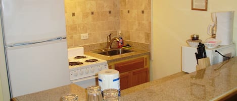 A kitchen with a refrigerator, stove, sink, and countertop.