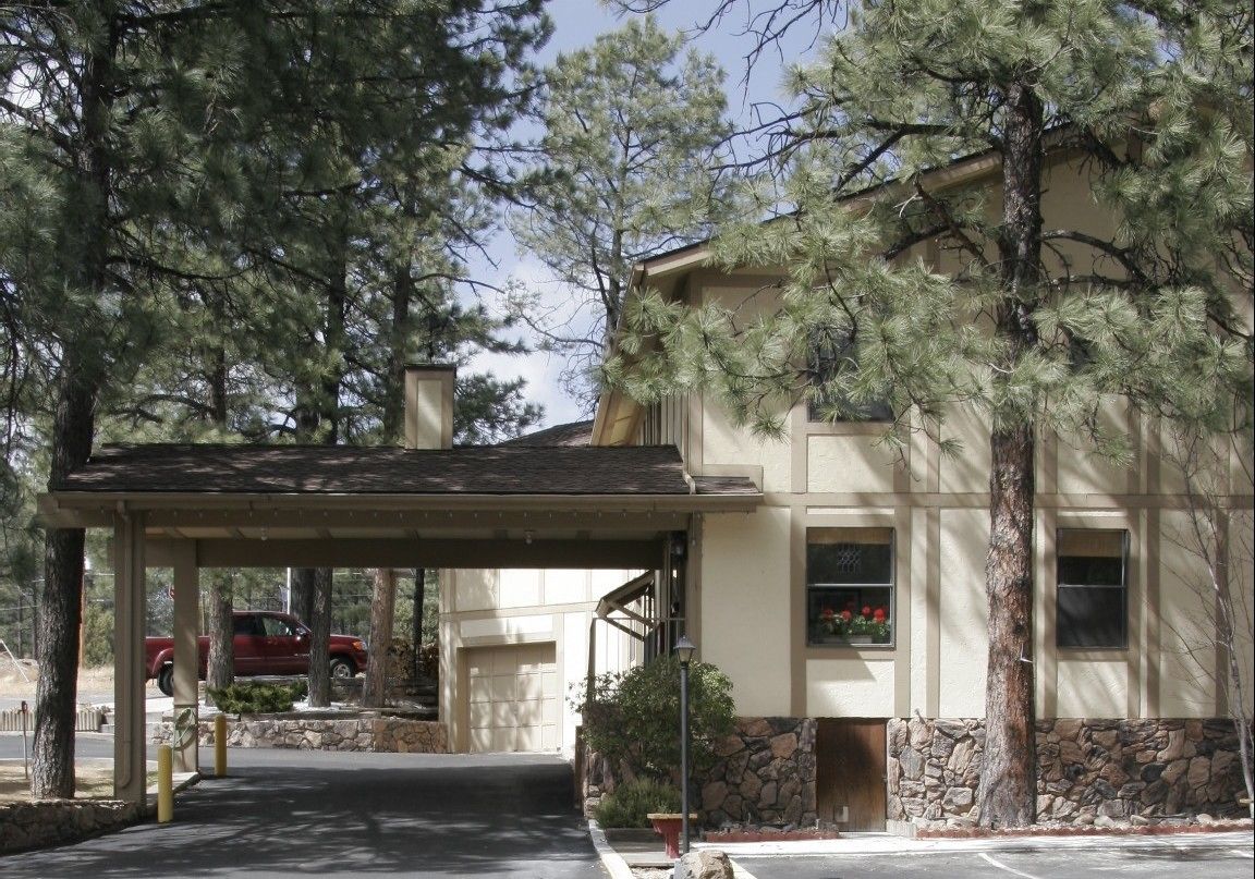 A building with a covered entrance, stone foundation, and windows with flower boxes.