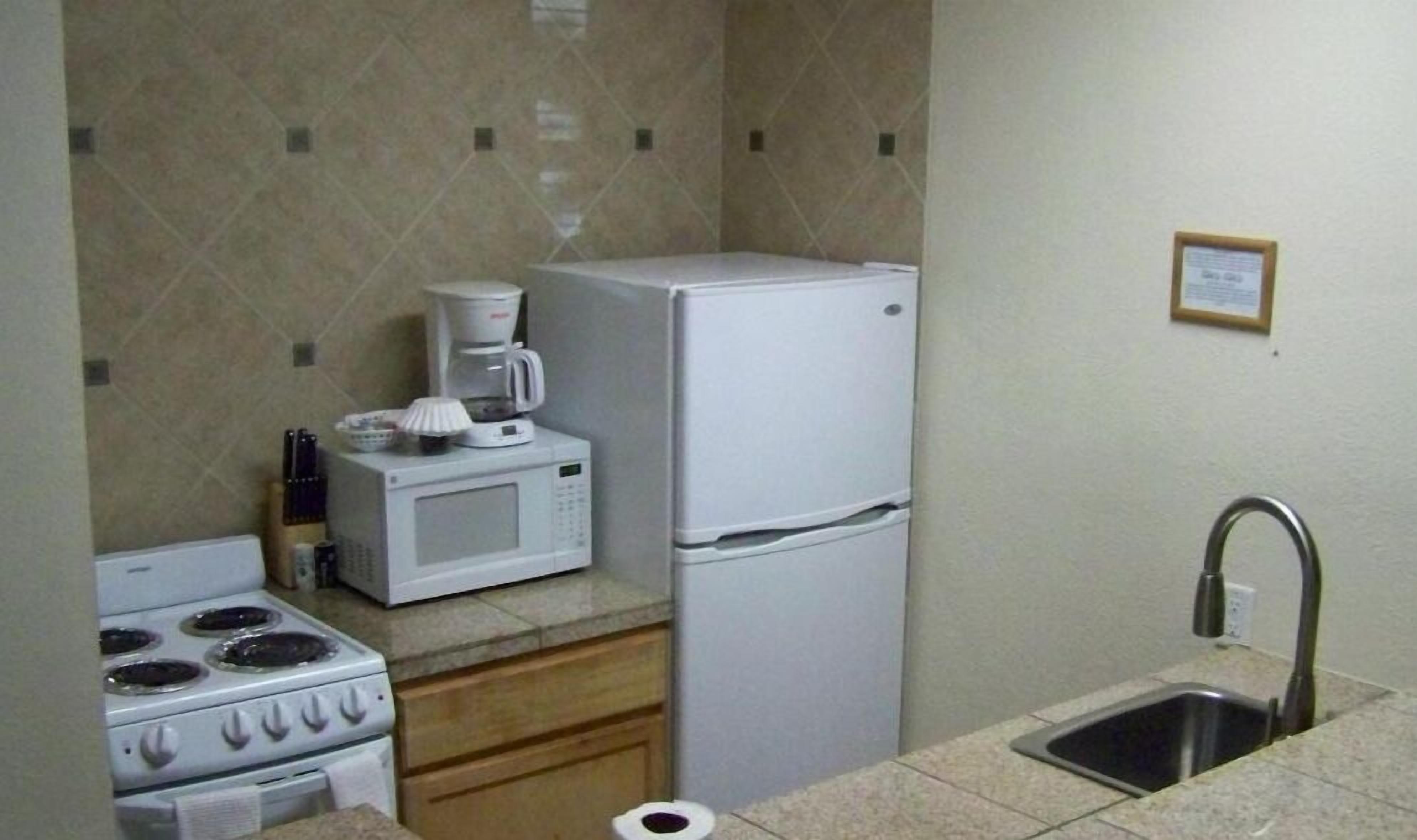 A compact kitchen with a stove, microwave, refrigerator, and sink.