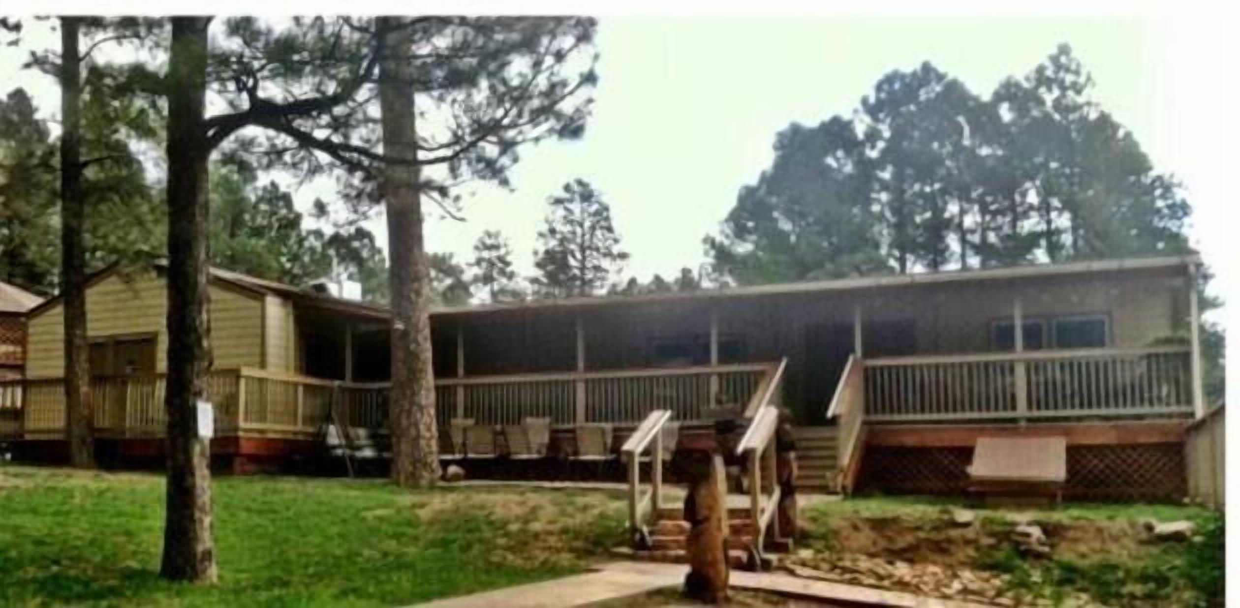 A two-story mobile home with a covered porch and a small deck.
