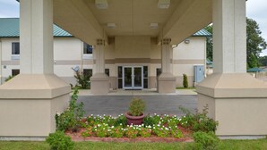 A building entrance with a covered walkway, columns, and a flower bed. - Star City Inn & Suites (Star City)