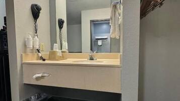 A hotel bathroom with a sink, mirror, and hairdryer.