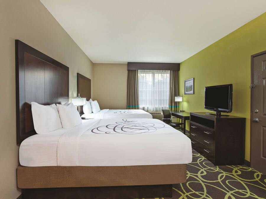 Ein Hotelzimmer mit einem großen Bett, einem Schreibtisch, einem Fernseher und einem Kleiderschrank.
