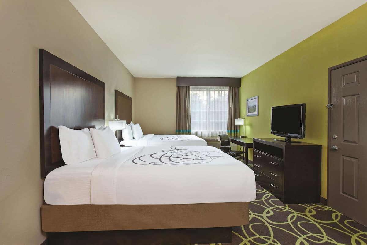 A hotel room with a bed, a desk, a television, and a door.