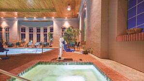 Uma piscina interior com espreguiçadeiras e uma banheira de hidromassagem.