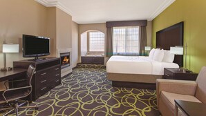 Quarto de hotel com cama, secretária, televisão, lareira e vista exterior.
