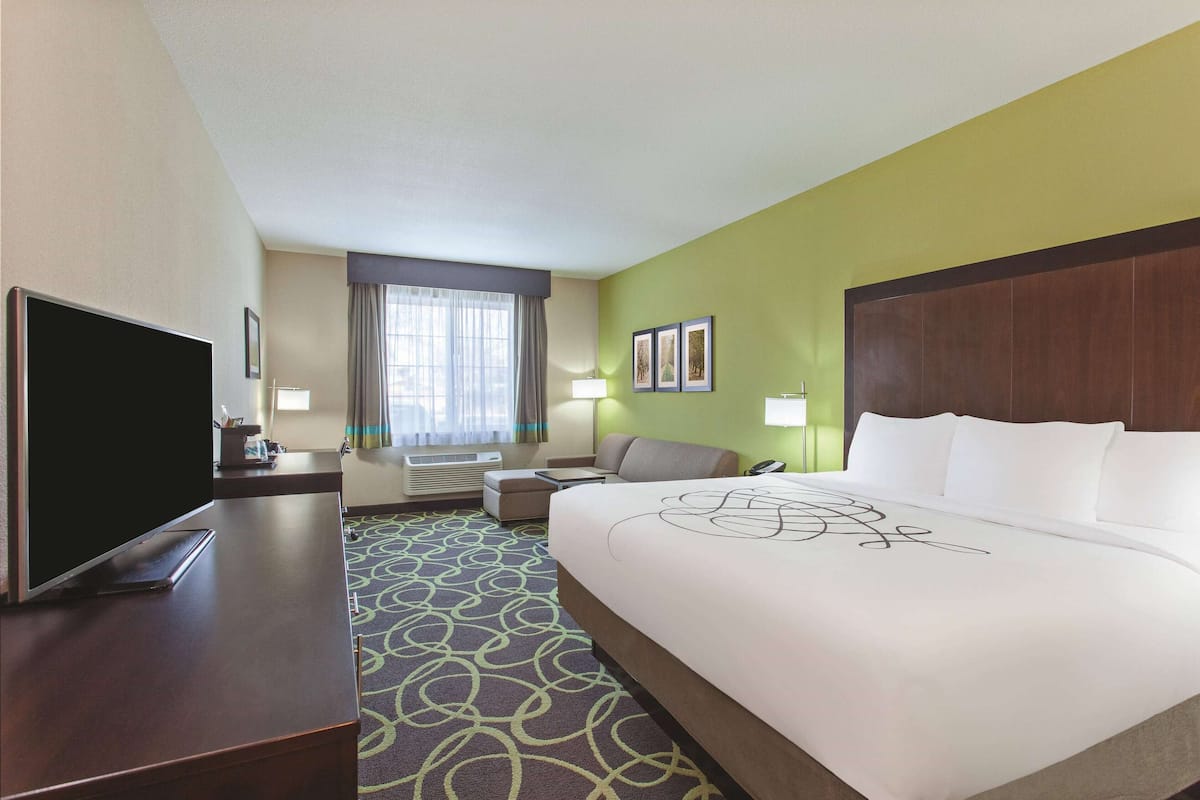 A hotel room with a large bed, a flat-screen TV, a sofa, and a desk.