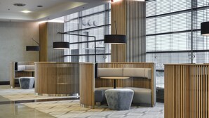 Eine moderne Lobby mit geometrischem Bodenmuster, zeitgemäßer Sitzmöblierung und vertikalen Holzpaneelen.