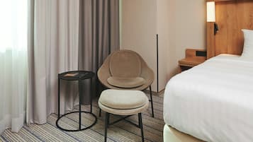 Ein Hotelzimmer mit Bett, Sessel, kleinem Tisch und Nachttisch.