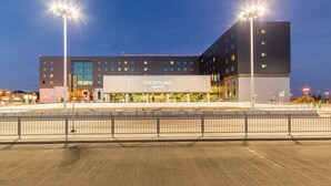Un hôtel Courtyard Marriott au design moderne, avec une grande enseigne, de nombreux étages et une façade bien éclairée.