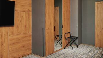 A modern room with wooden panel walls, a flat-screen TV mounted on the wall, and a pair of black chairs.
