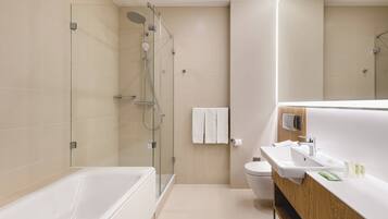 A modern bathroom with a glass-enclosed shower, a bathtub, a sink with a wooden vanity, and a toilet.