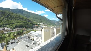 Une vue depuis une fenêtre donnant sur une ville, avec ses bâtiments et ses montagnes.
