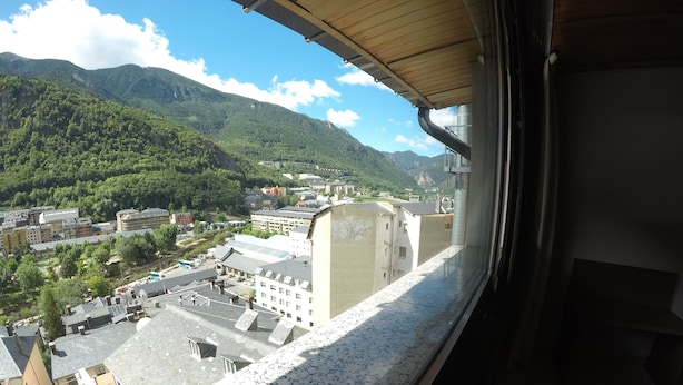 Vista desde una ventana que da a un pueblo con edificios y montañas.