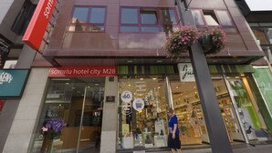 Entrada de un hotel con un cartel que dice 'Somriu Hotel City M28'.