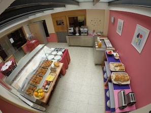 Buffet de l'esmorzar amb diferents plats, una estació de cafè i una presentació de fruita.