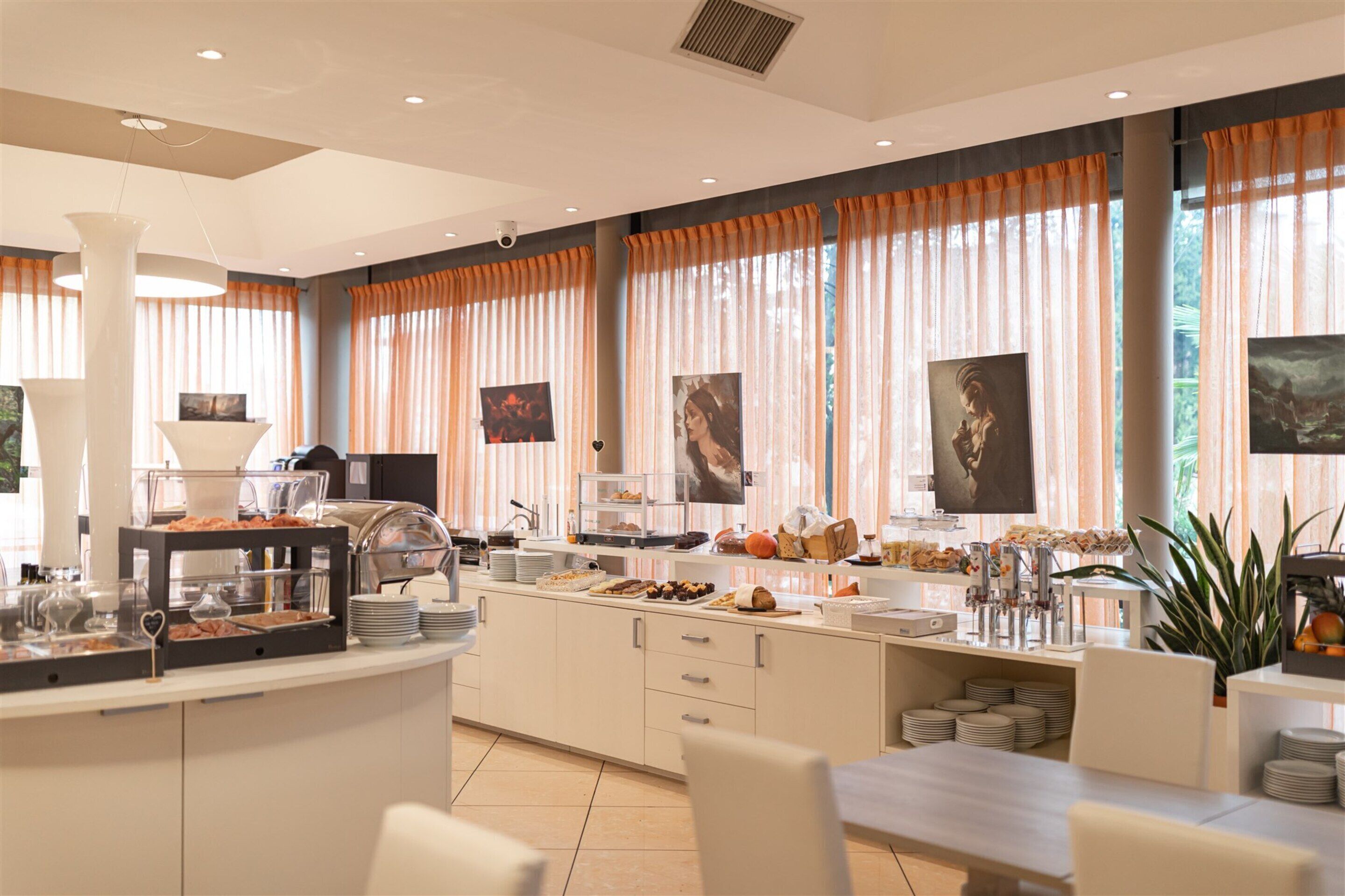 A modern breakfast bar with a variety of food items, a coffee station, and a seating area with chairs and a table.