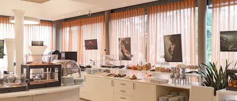 A modern breakfast bar with a variety of food items, a coffee station, and a seating area with chairs and a table.
