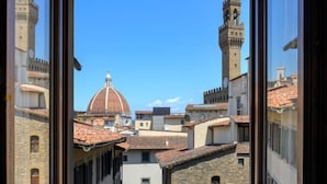 Vista a través de una ventana de un paisaje urbano con edificios históricos, una cúpula destacada y una torre del reloj.