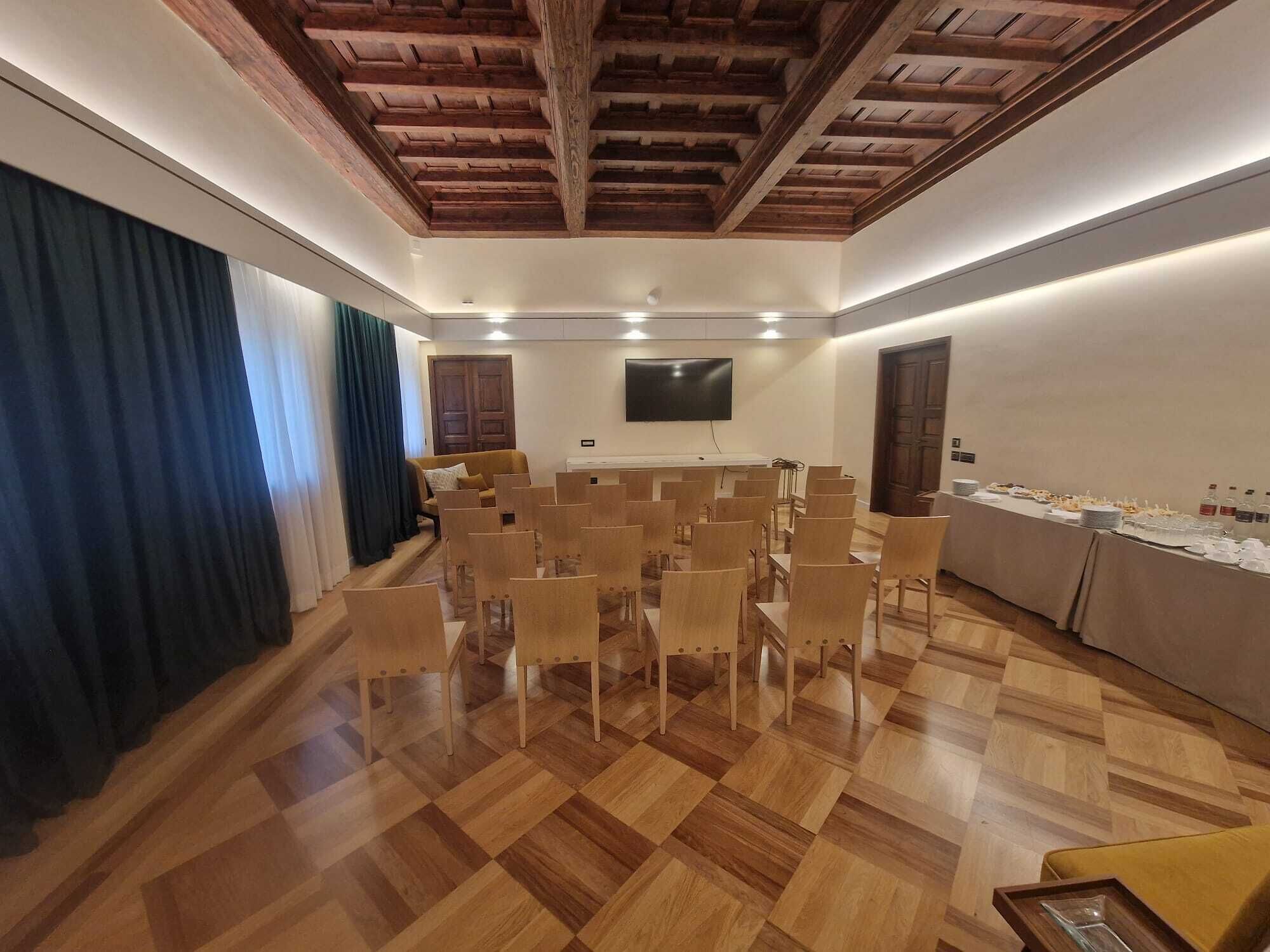 Une salle de conférence avec des chaises en bois, une grande table, un téléviseur à écran plat et un plafond en bois.