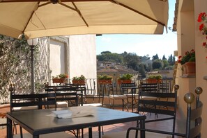 Relax on the outdoor terrace with scenic views of the town, surrounded by lush greenery and comfortable seating.