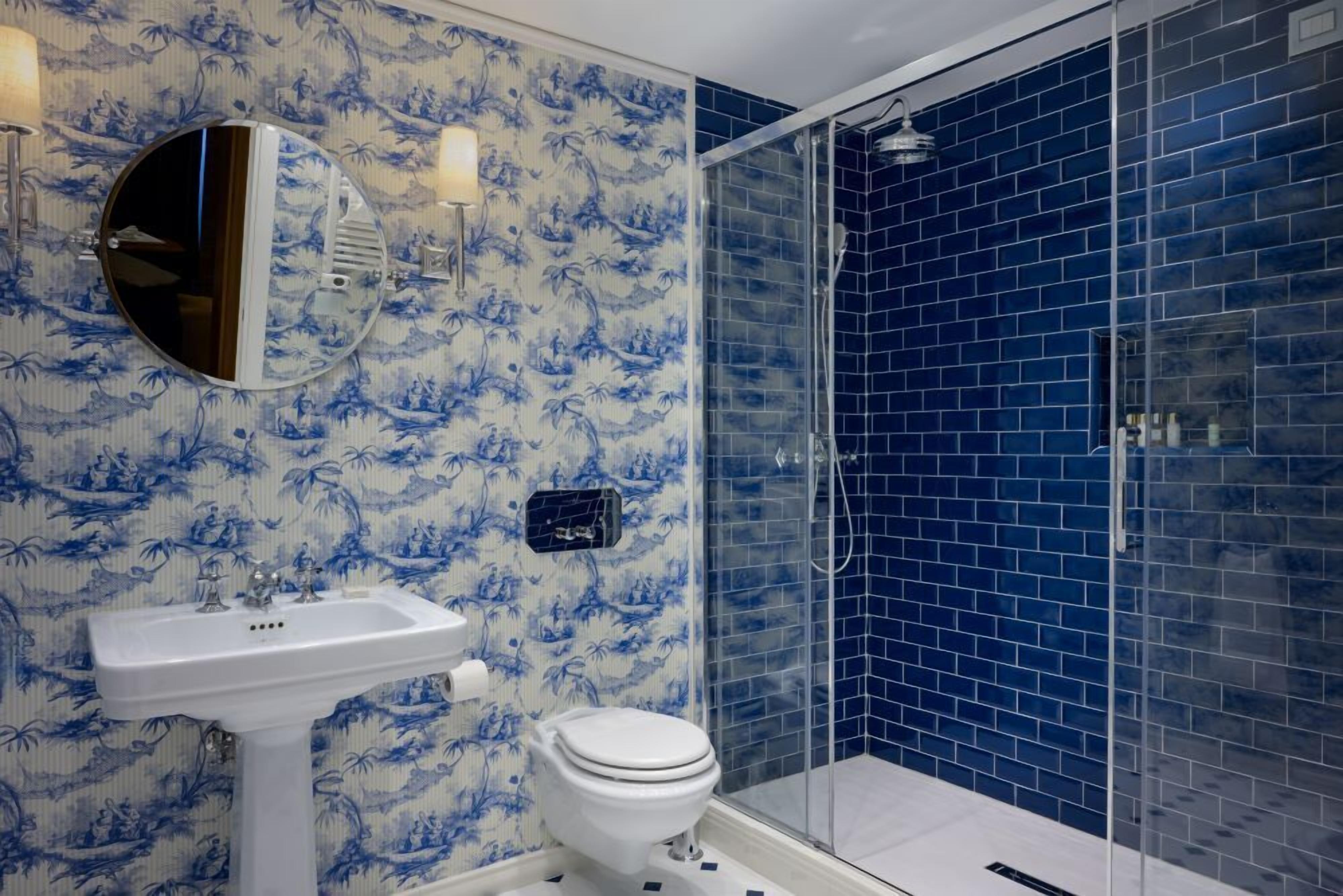 A bathroom with a white sink, toilet, and a glass shower enclosure.