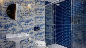 A bathroom with a white sink, toilet, and a glass shower enclosure.