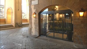 Entrada de hotel con arcos de piedra, puerta de cristal y plantas en macetas.