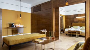 A modern hotel room with a wooden accent wall, a bed, a bench, a small table with a book, and a mirror.