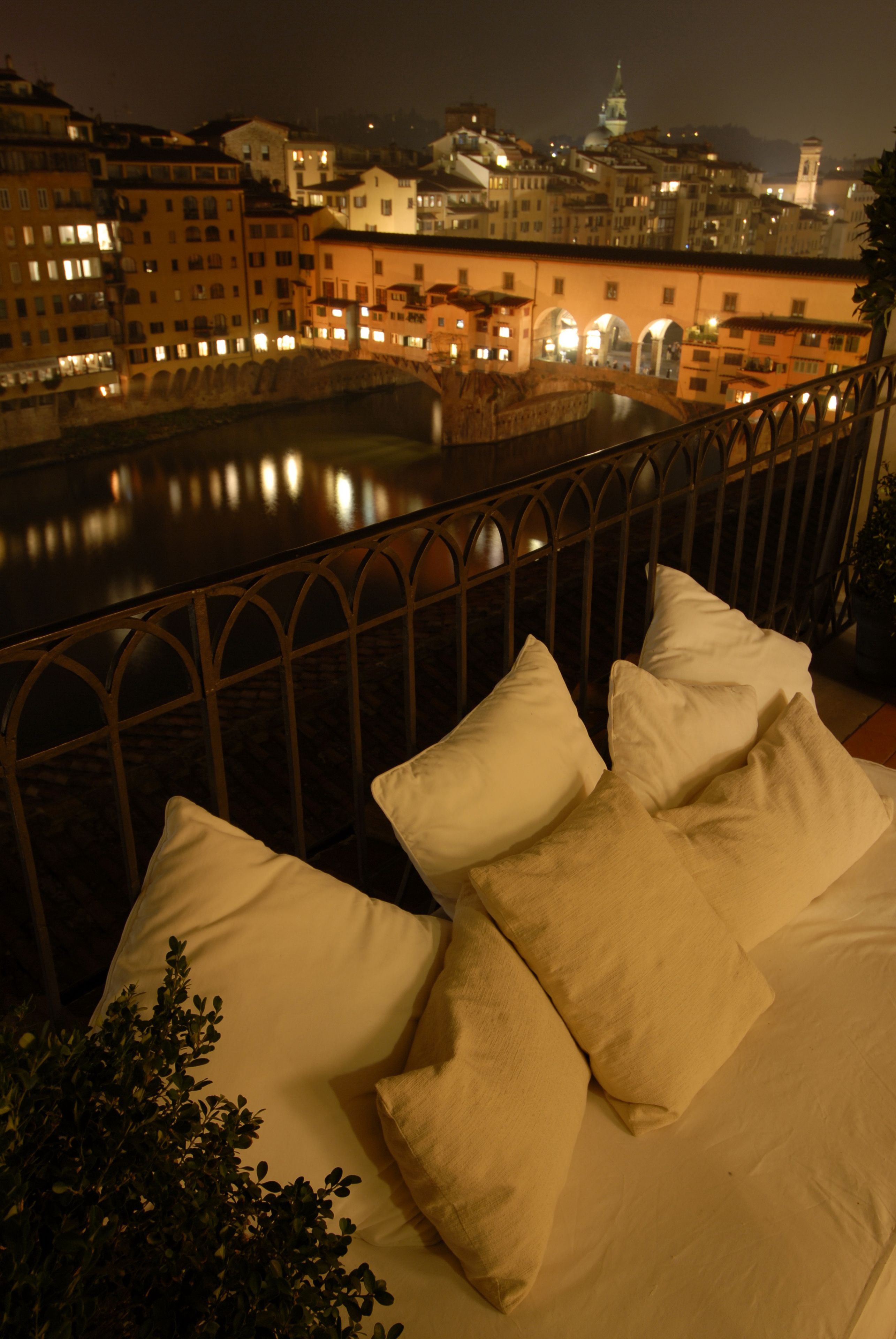 A balcony with a view of a river and cityscape at night.