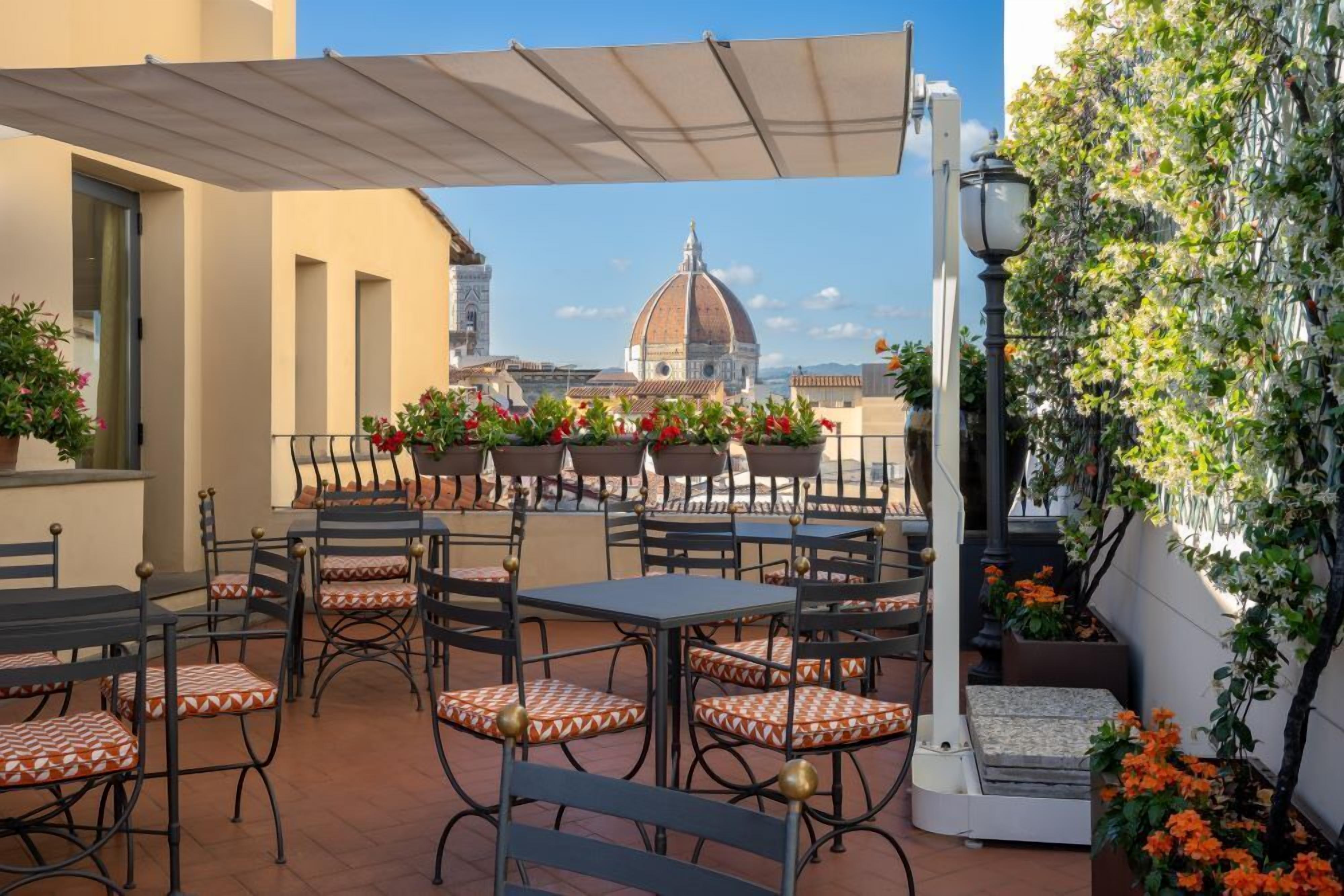 Une terrasse extérieure avec des tables et des chaises, une vue sur un dôme et un lampadaire.
