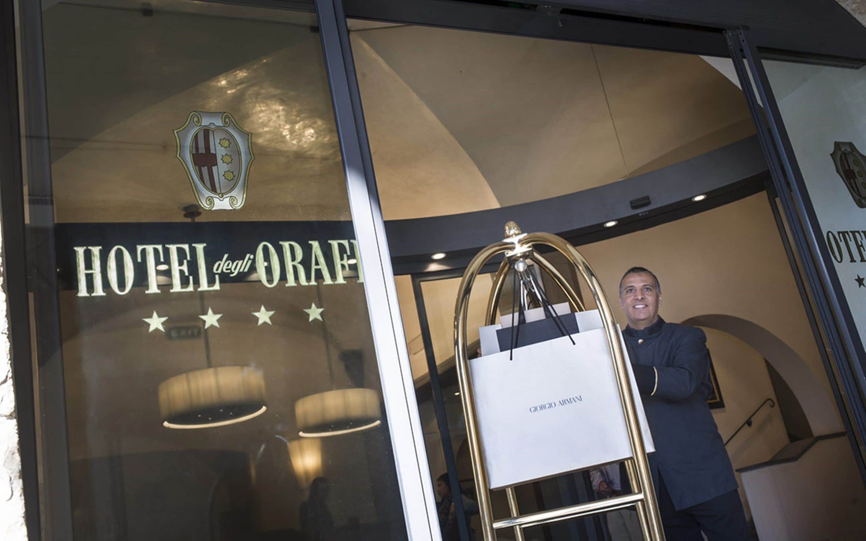 Entrada de un hotel con un letrero que dice "HOTEL degli ORAFI" y un logotipo encima.