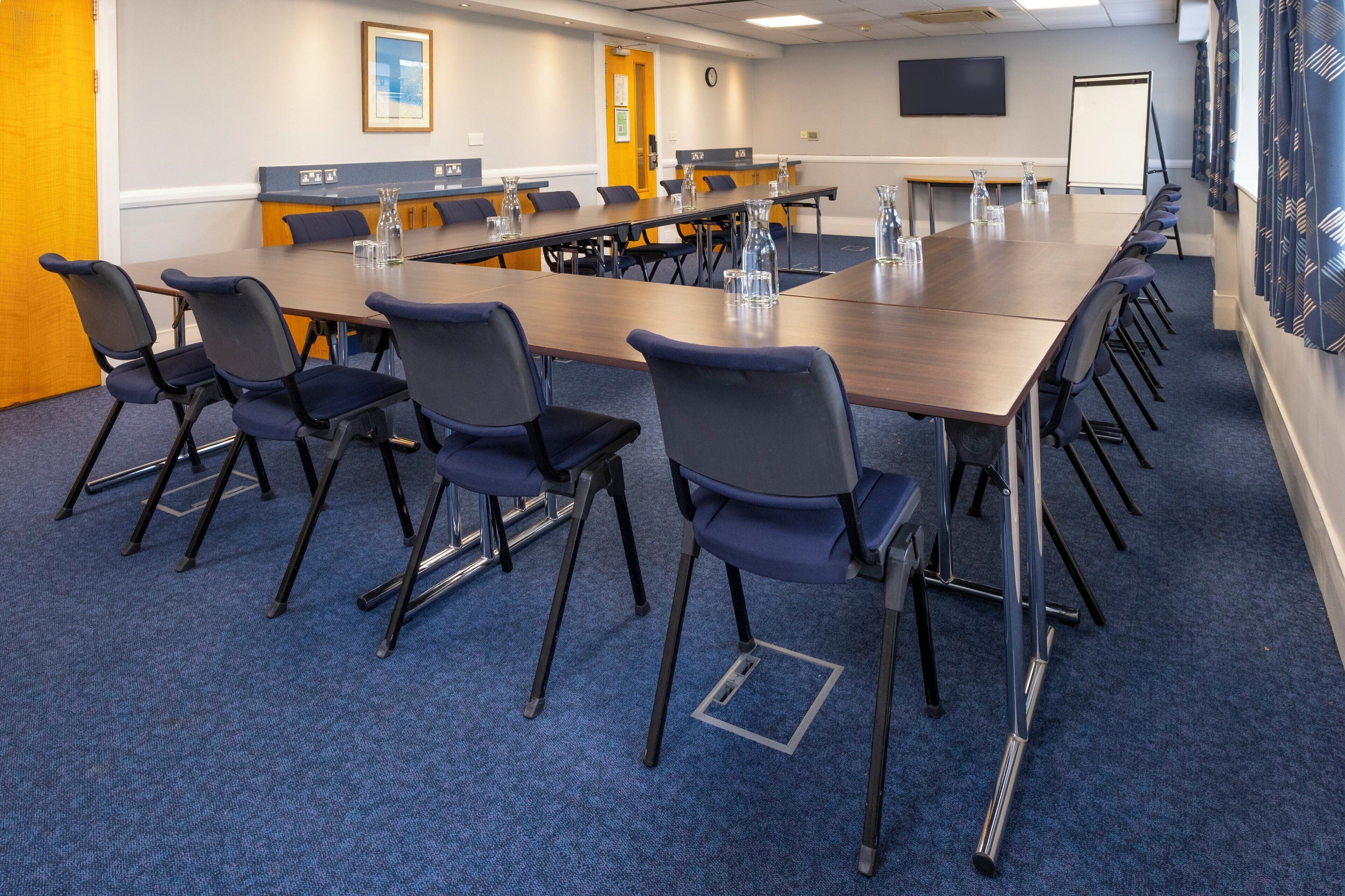 A conference room with a long table, chairs, and a whiteboard.