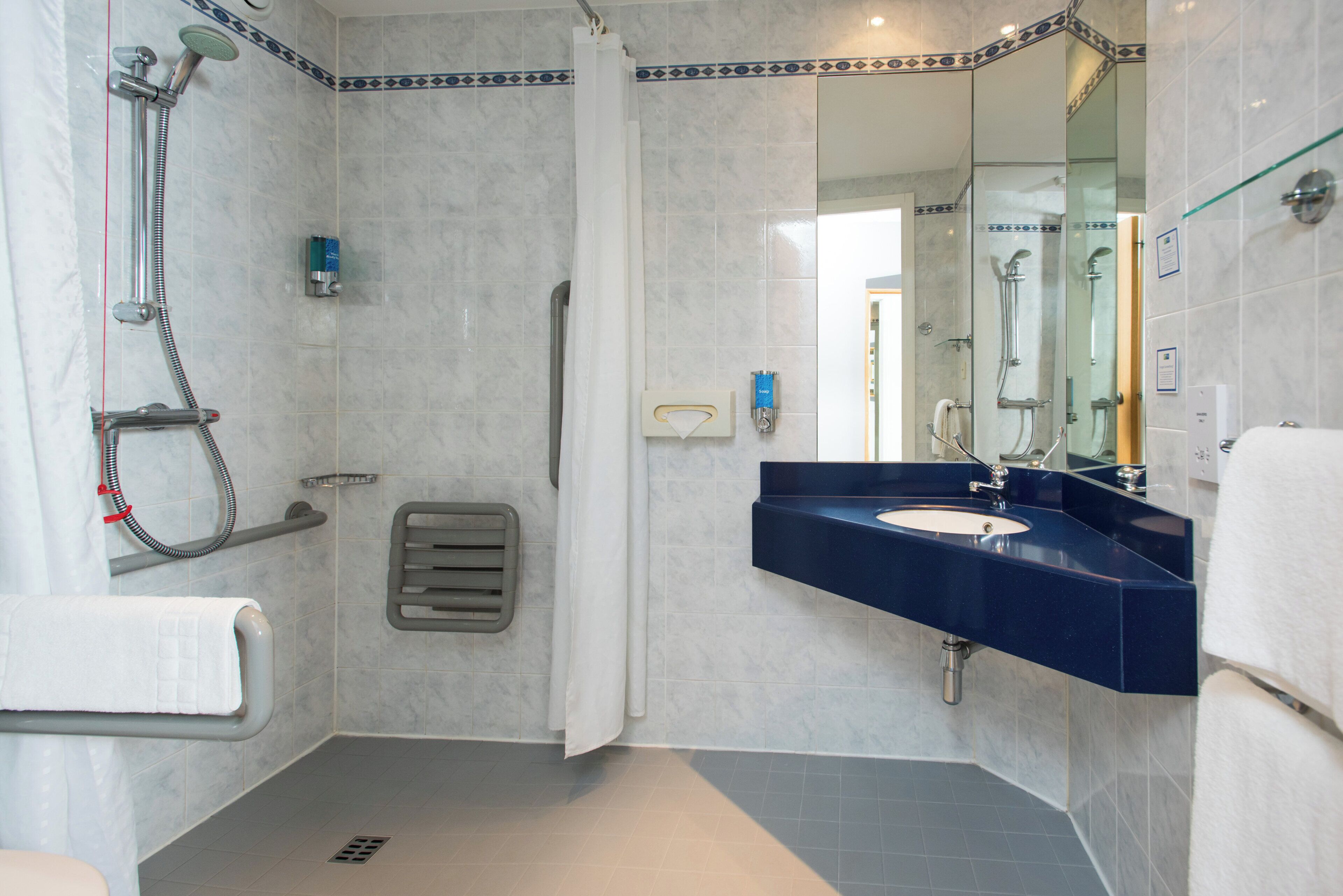 A bathroom with a shower, a sink, and a mirror.