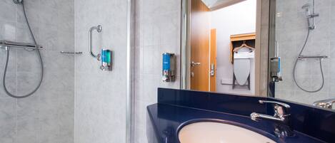 A modern bathroom with a large mirror, a bathtub, and a sink.