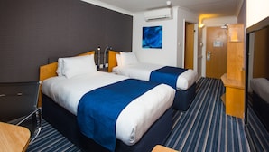 A hotel room with two beds, a desk, and a chair.