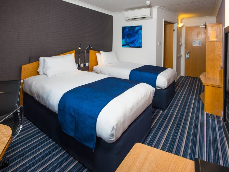 Ett hotellrum med två sängar, ett skrivbord och en stol.