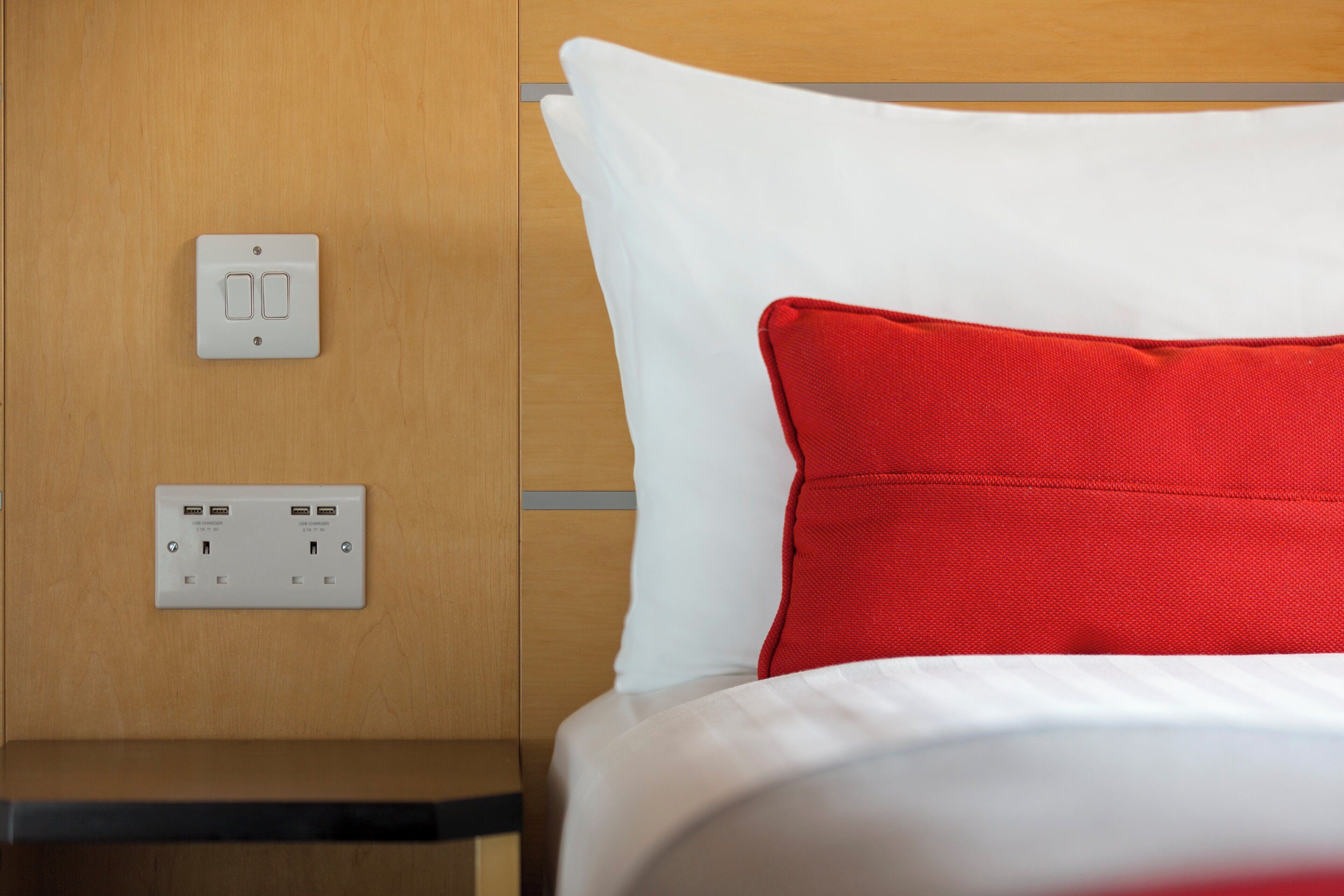 A hotel room with a bed, a nightstand, and a wall-mounted USB charging station.