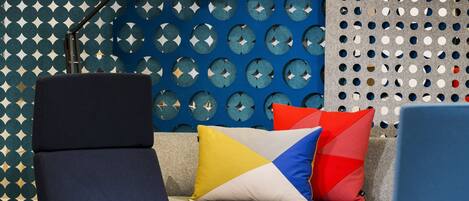 A modern lounge area with a blue patterned wall, a round table, and two armchairs.
