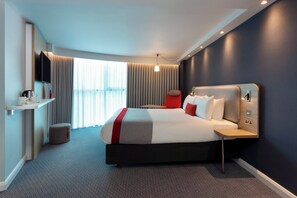 A modern hotel room with a large bed, a bedside table, a TV, and a window with curtains. - Holiday Inn Express London - Park Royal by IHG (London)