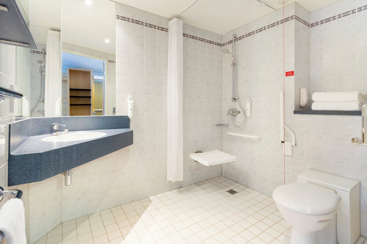 Une salle de bain moderne équipée d’un lavabo, de toilettes, d’une douche et d’un porte-serviettes.