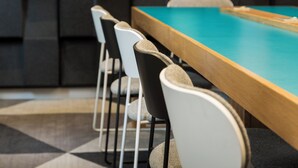 A pool table with chairs and a wall with soundproofing panels. - Holiday Inn Express London - Park Royal by IHG (London)