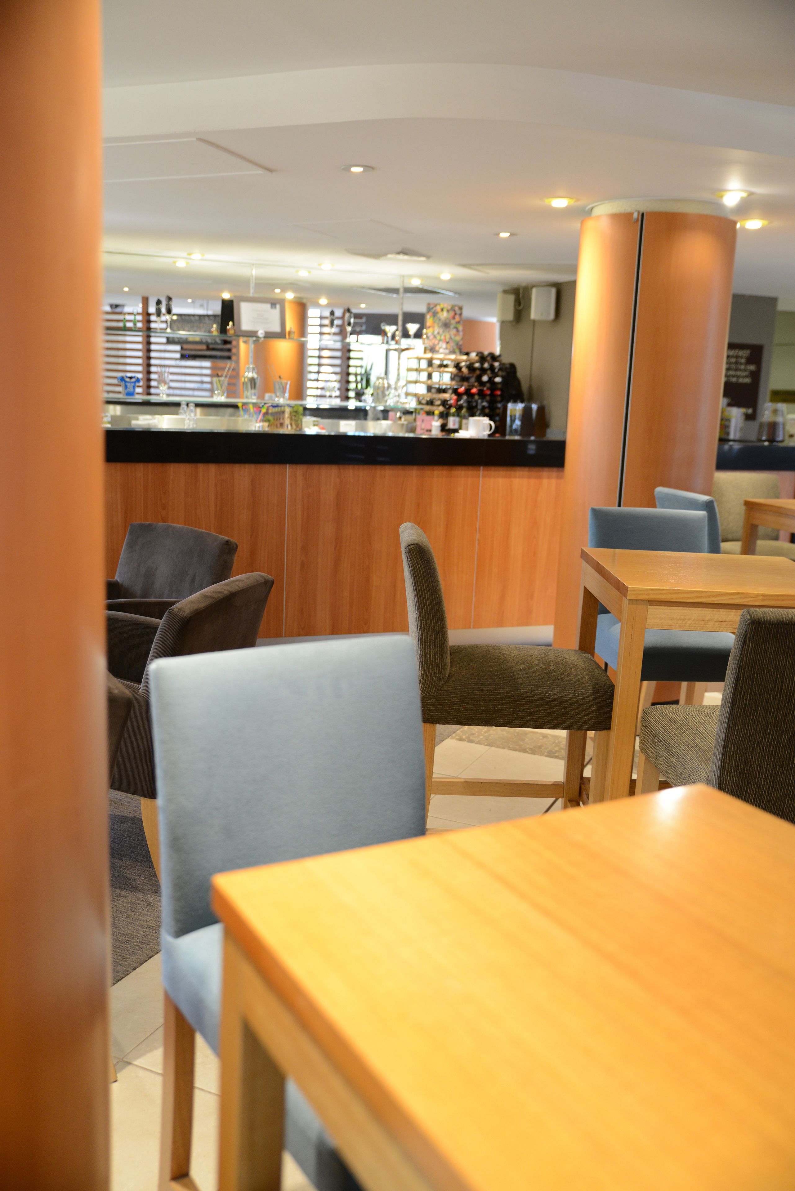 A hotel lobby with a bar area, seating arrangements, and a wooden reception desk.
