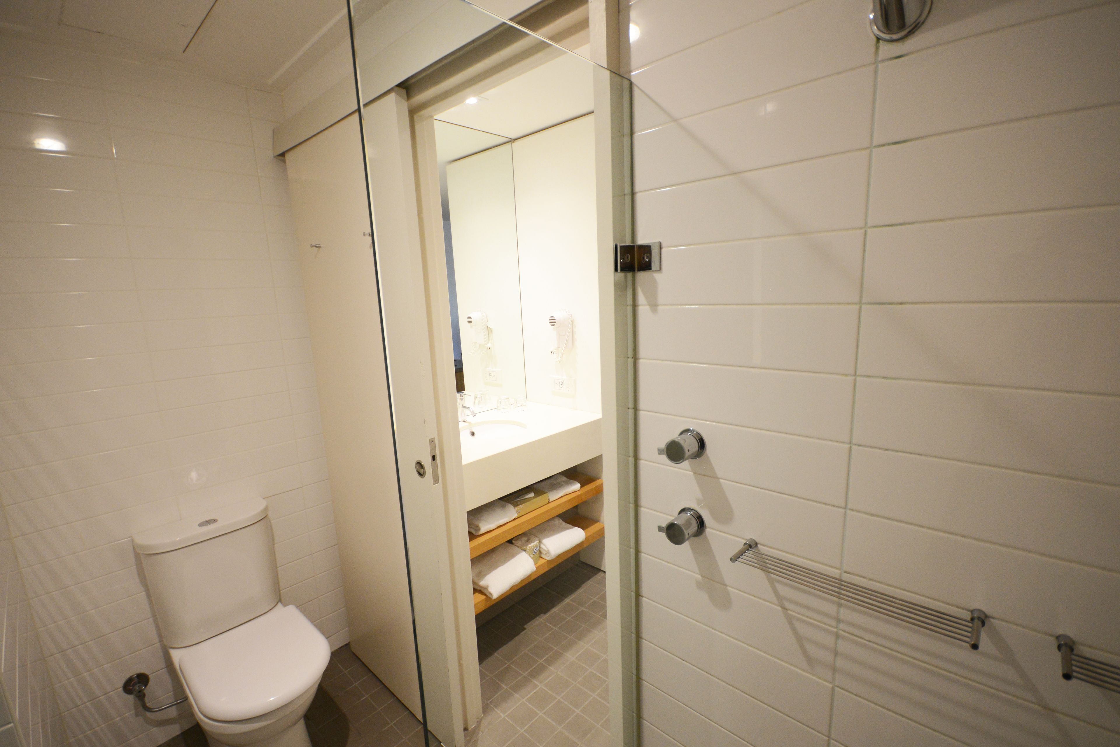 Un baño moderno con inodoro, cabina de ducha de vidrio y zona de lavamanos con toallas.