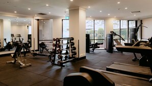 A gym with various exercise equipment, large windows, and a mirrored wall.